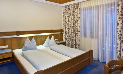 Gemütliches Schlafzimmer mit warmem Holz, bequemen Betten und floralen Vorhängen für entspannte Nächte.