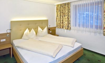 Gemütliches Schlafzimmer mit großem Bett, Nachttisch und floralen Vorhängen für eine angenehme Nachtruhe.